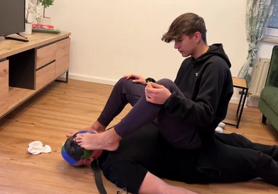 German master sitting on feet licking boy